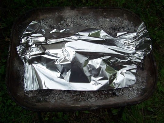 On entoure les oignons de braises et cendres, puis on les recouvre d'une feuille d'alu